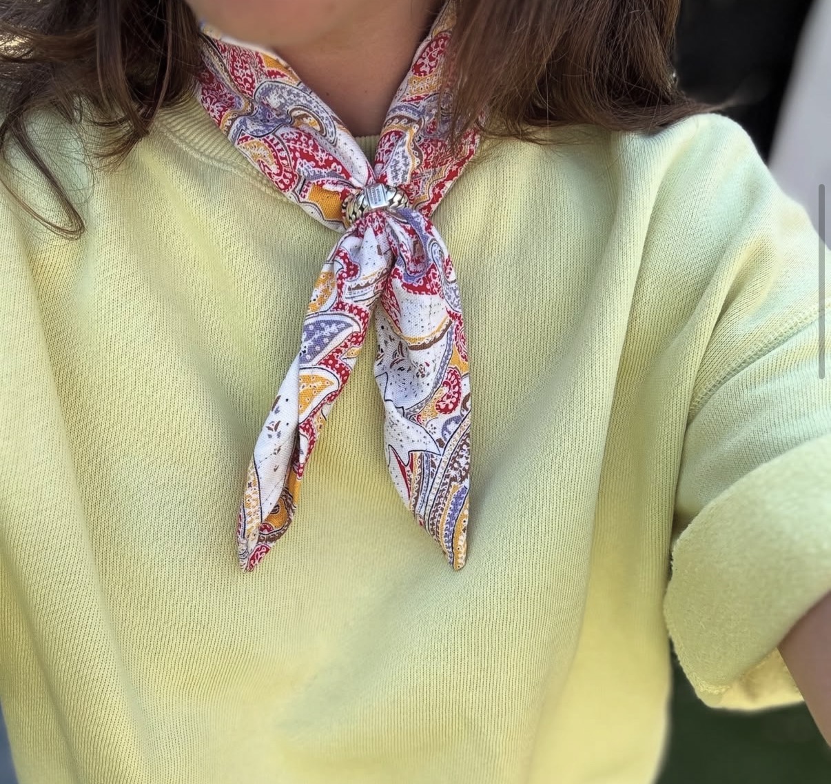 Misa scarf tied at the neck over a yellow knit